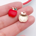 Close-up of small apple-shaped charms with red enamel and gold finish for DIY crafts - Red Apple (10851)