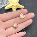 Pendentifs coquillages dorés KC pour bijoux DIY, présentés en main pour la taille - Petit Coquillage (11599)