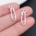 Pair of silver safety pin charms held by hand showing size and mirror finish - Safety Pin Charm (20204)