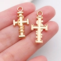 Mano sosteniendo dos colgantes de cruz dorados con texturas de cuerda para collares DIY - Cruz Envuelta en Cuerda 26x12mm (20341)