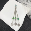 Macro shot of silver tassel earrings with green beads and Celtic knot charms - Green Beads Antique Silver Tassel (21111)