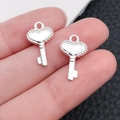 Polished silver heart key charms with beaded texture held for size reference - Bright Silver Dotted Heart Key (20959)