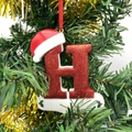 Sparkly red letter H Christmas ornament with Santa hat hanging on a festive tree branch - Letter H (Style H)