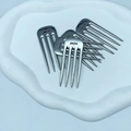 Macro detail of five silver metal hair combs with JACK engraving on a white plate - JACK Label