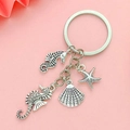 Detailed close-up of seahorse, starfish, and scallop metal charms on a sturdy keyring - Antique Silver (ER551)