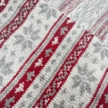 Close-up of red and grey Christmas jacquard knit fabric with snowflake patterns - Grey + Red