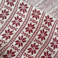 Macro detail of red and white Nordic snowflake pattern on knitted wool fabric texture - White