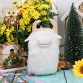 Adorable white Highland Cow plush toy with pink horns on a rustic floral background - White
