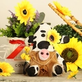 Nahaufnahme der Kuh-Zwergpuppe mit Sonnenblumenhut und einem kleinen Kupferglockendetail - Herrenstil