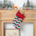 Close-up of knit Christmas stocking with wavy stripes and colorful plush pom poms - Knitted Red Green Stripe Stocking