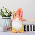 Gnome de Pâques en peluche avec oreilles de lapin sur des livres près de fleurs blanches - Style Lapin Orange