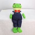 Detailed view of green plush frog wearing a white shirt and blue denim overalls - Frog