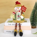 Muñeco de nieve navideño de felpa con chaleco de acebo sentado sobre unos libros - Muñeco de nieve