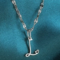 Macro-opname van de zilveren letter L hart hanger aan een gedraaide glanzende ketting - Staal-L