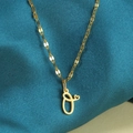 Detailopname van gouden letter O-hanger met hartje op een zijdeachtige achtergrond - Goud-O