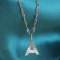 Macro view of silver letter A pendant with sunray texture on blue silk background - Letter A / Silver