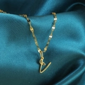 Close-up van gouden letter L ketting met hartdetail op groenblauwe zijden stof - Goud-V