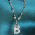 Silver alphabet B pendant necklace with radial texture on a blue silk background - Letter B / Silver
