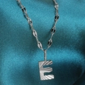 Polished stainless steel necklace featuring a radiant letter E pendant on green silk fabric - Letter E / Silver