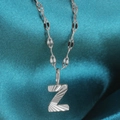 Silver alphabet Z pendant necklace with sunburst texture on a blue silk fabric background - Letter Z / Silver