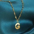 Gouden halsketting met letter G-hanger en plissé-textuur op donkerzijden achtergrond - Goud-G