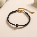 Handgemaakte zwarte kralenarmband met gouden letter E bedeltje en een karabijnsluiting - Letter - E