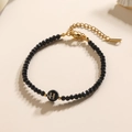 Elegante zwarte kralenarmband met gouden sluiting en detail van de gouden letter H - Letter - H