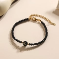 Minimalistische zwarte kralenarmband met gouden letter K bedeltje en roestvrijstalen slot - Letter - K