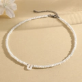 White beaded necklace featuring a shell-like letter U pendant and silver clasp closure - U (SHNK2434)
