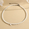 White beaded necklace featuring a white shell X letter pendant with adjustable silver chain - X (SHNK2434)