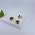 Detailweergave van drie gouden ringen met groene zirkoon smiley op een stenen plaat - Groen Pave Lachend Gezicht Stijl (#2)