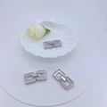Interlocking square zircon jewelry clasps in silver finish on a decorative white tray - Silver