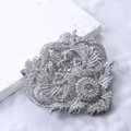 Makro-Detail einer silbernen Phönix-Brosche mit Zirkonia und grünen Edelsteinen - Silber Stil (#3)