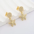 Nahaufnahme goldener Seestern-Ohrringe mit Zirkonia-Steinen auf weißen Wellen-Requisiten - Fünf-Punkt-Seestern-Stil (#8)