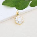 Macro detail of a gold-plated sea turtle pendant on a white stone and green leaf background - White Gold Sea Turtle Pendant (#13)