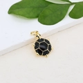 Macro view of a gold-plated sea turtle pendant with black enamel shell on stone - Black Gold Sea Turtle Pendant (#15)