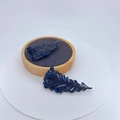 Exquisite dunkelblaue Federbrosche mit Zirkonia-Mikropavé auf einem hölzernen Schmuckständer - Blauer Strass