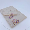 Detailed macro view of purple enamel and gold-plated copper earrings with zircon stones - Purple