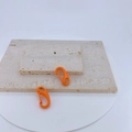 Detail view of glossy orange lobster clasp hooks on white marble for DIY jewelry making - Bright Orange