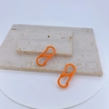Detail of two bright orange S-shaped carabiners with spring clips on stone travertine - Bright Orange