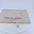 Detail showing white matte spring snap hooks on beige stone texture for DIY crafts - White