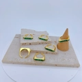 Verstelbare goudkleurige ringen met groene zirkoonstenen op beige stenen display - Groene Rechthoekige Steen Stijl