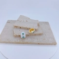 Detail of white evil eye charms with blue and yellow patterns on natural stone slabs - White Oval / Pendant Only (Without Chain)