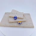 Detailed view of blue enamel evil eye charms on stacked beige stone tiles - Royal Blue Egg Shape / Pendant Only (Without Chain)