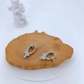 Macro detail of silver lobster clasps with full zircon inlay on a wooden stand - Silver Fish Silhouette Style (#6)