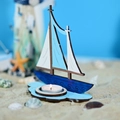Détail d'un bougeoir voilier en bois nautique sur sable avec des coquillages - Style Voilier