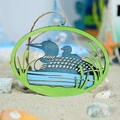 Detail of laser-cut wooden loon bird ornament with jute rope on sandy beach background - Duck