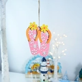 Close-up of pink wooden flip-flop wall hanging with floral patterns and twine rope - Flip-flops