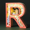 Macro view of illuminated letter R wooden LED light with festive winter carving scene - Letter R