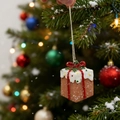 Close-up of a festive cake box ornament hanging on a snowy Christmas tree branch - Gift Box
